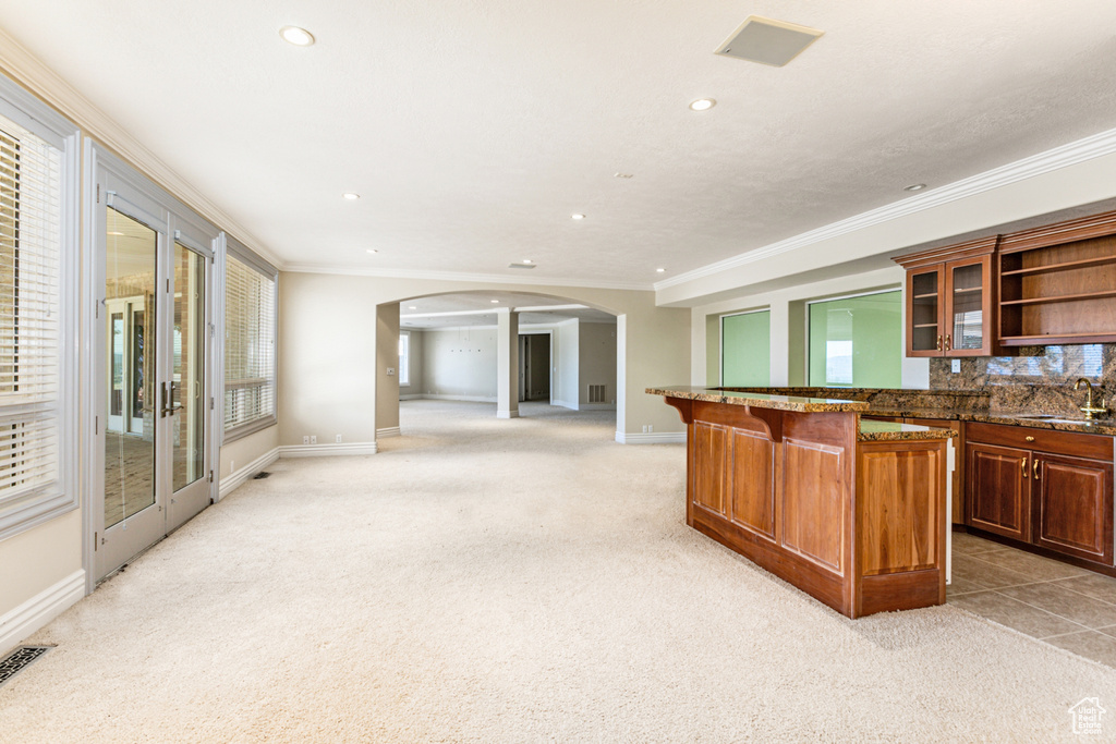 Kitchen featuring crown molding, a breakfast bar, sink, tasteful backsplash, and light colored carpet