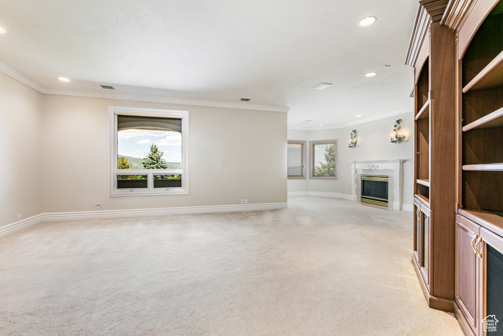 Unfurnished living room with a high end fireplace, ornamental molding, and light carpet