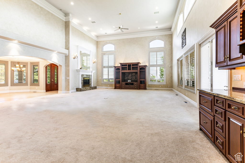 Living room featuring crown molding, ceiling fan with notable chandelier, and light colored carpet