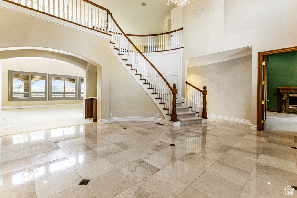 Stairs featuring tile floors, ornamental molding, and a high ceiling