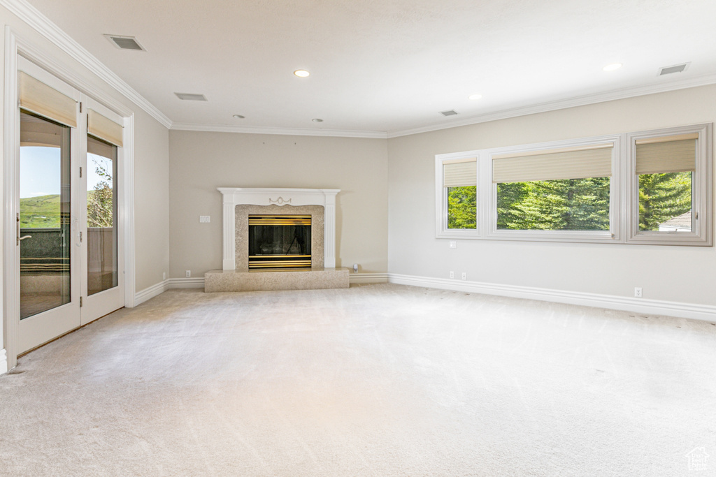 Unfurnished living room featuring crown molding, carpet flooring, and a fireplace