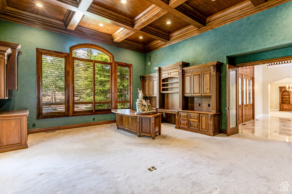 Unfurnished office featuring beamed ceiling, coffered ceiling, and light colored carpet