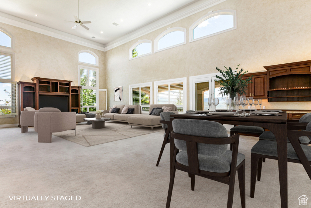 Carpeted dining space with a high ceiling, crown molding, and ceiling fan