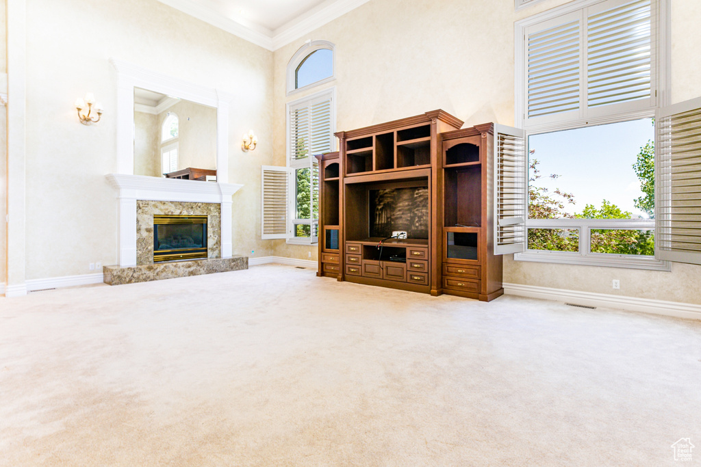 Unfurnished living room featuring a premium fireplace, carpet floors, and a towering ceiling