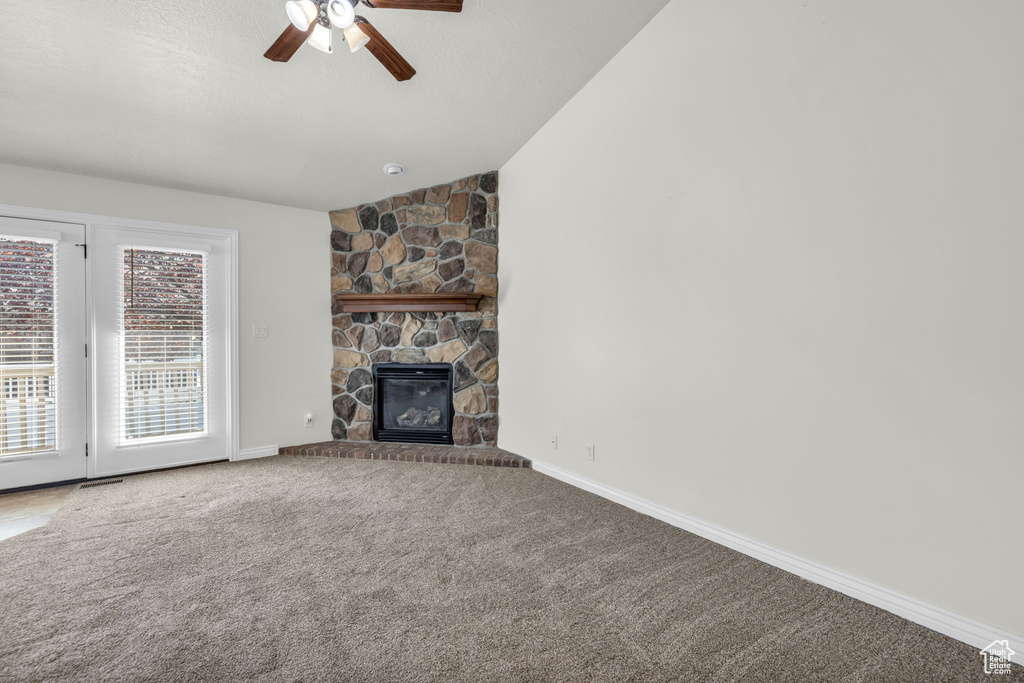 Unfurnished living room with light colored carpet, ceiling fan, vaulted ceiling, and a fireplace