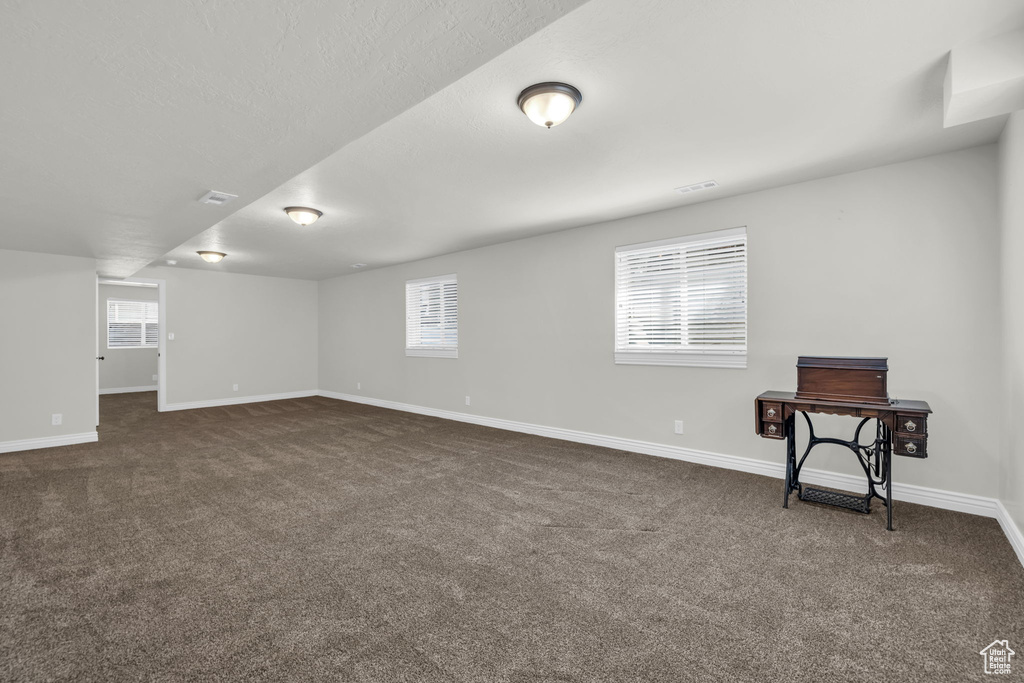 Basement featuring a healthy amount of sunlight and dark colored carpet