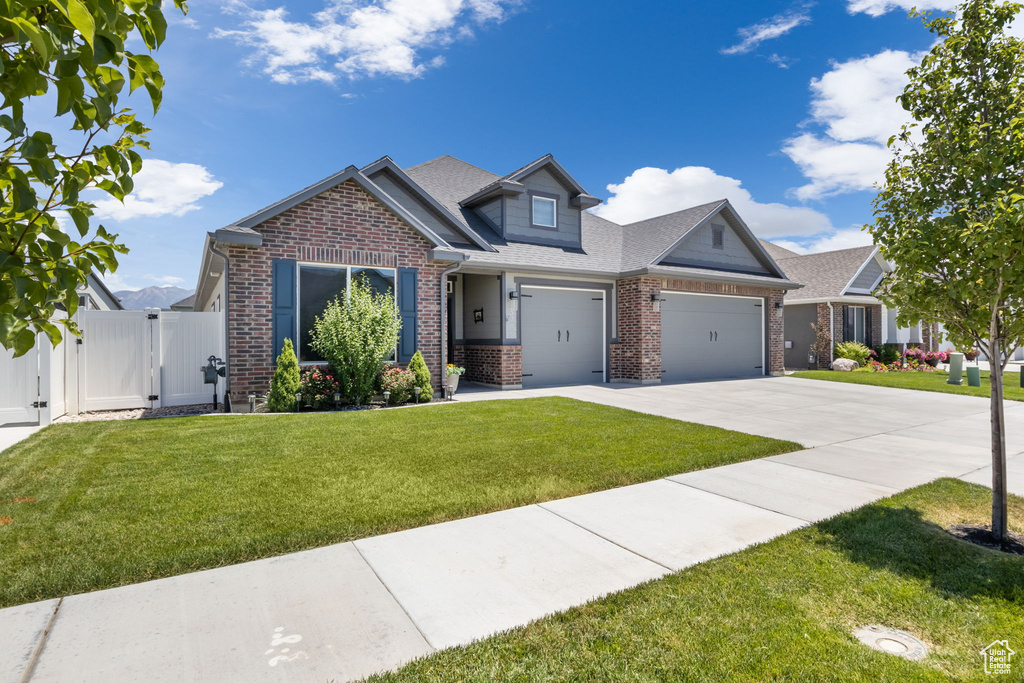 Craftsman inspired home with a garage and a front lawn