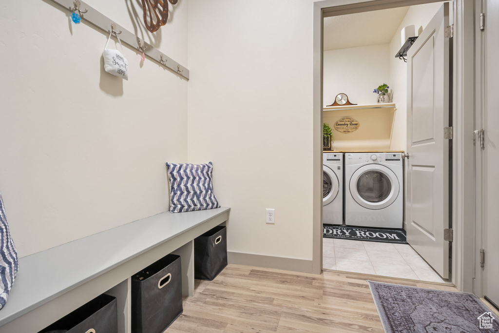 Clothes washing area featuring a barn door, light tile flooring, and washing machine and dryer