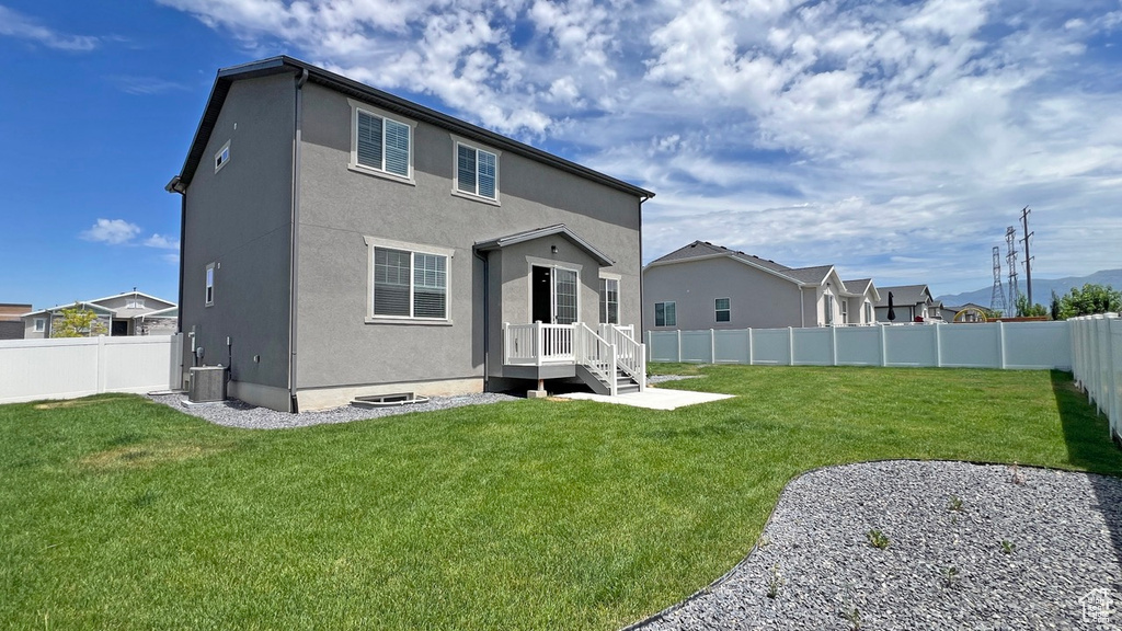 Rear view of house featuring a yard, central AC, and a patio area