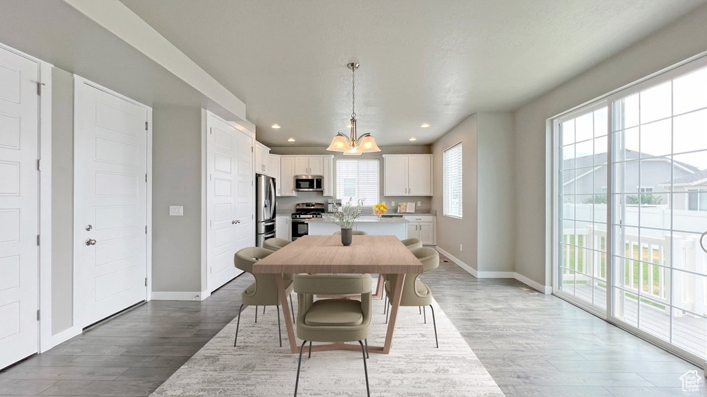 Dining area featuring sink, light wood-type flooring, and an inviting chandelier