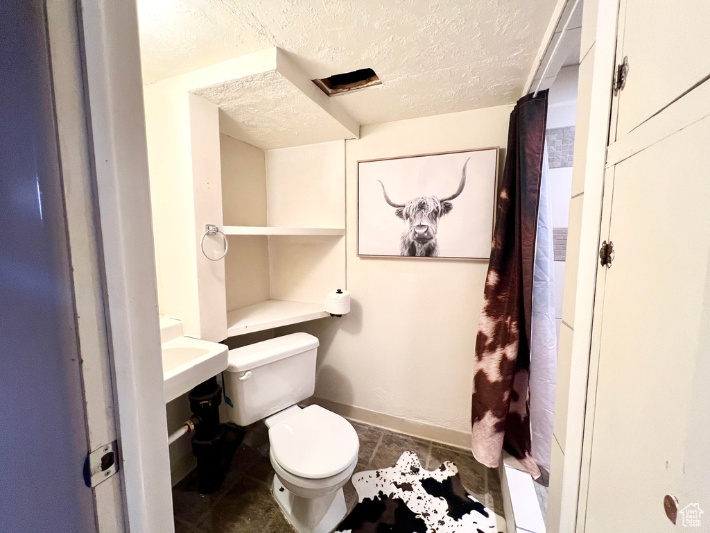 Bathroom featuring a textured ceiling, tile patterned flooring, and toilet