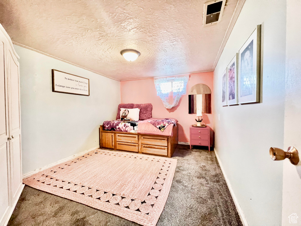 Bedroom with a textured ceiling, carpet flooring, and ornamental molding