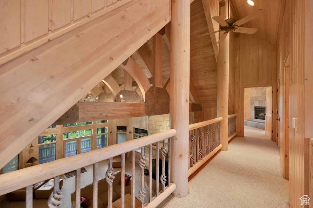 Hallway with beamed ceiling, high vaulted ceiling, wooden ceiling, and light colored carpet