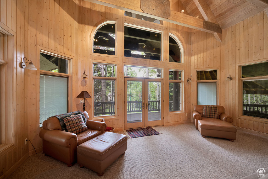 Living area featuring beam ceiling, wooden ceiling, high vaulted ceiling, and wood walls