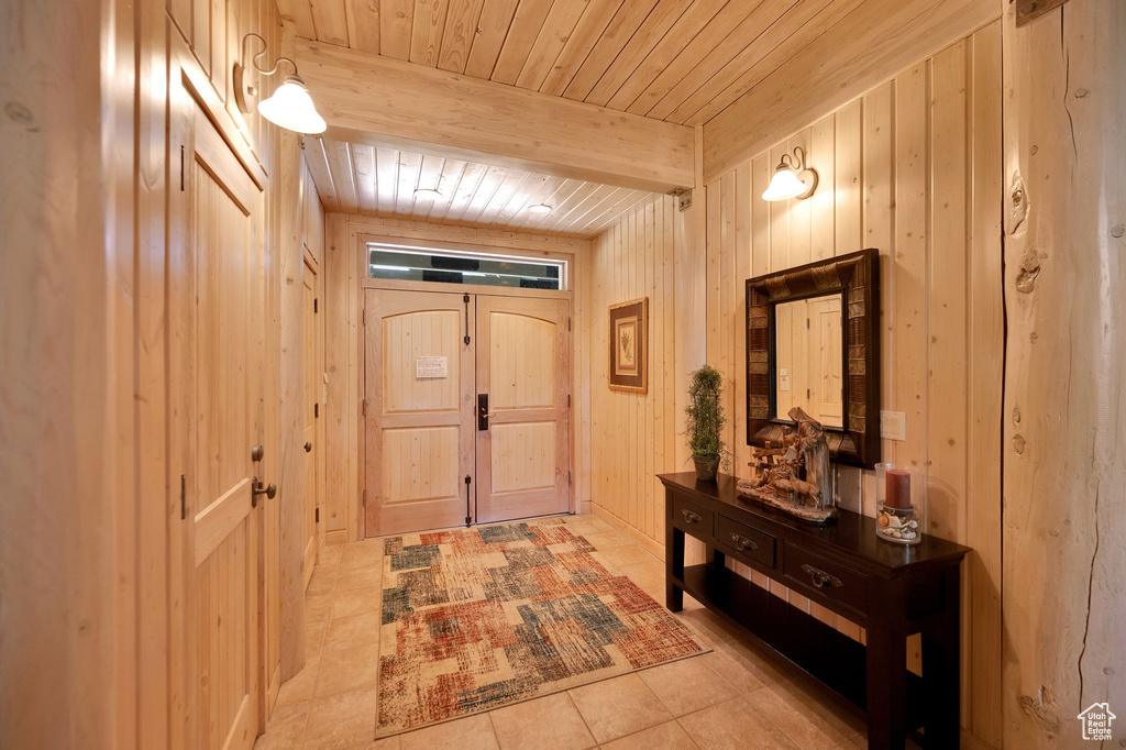 Hallway featuring wood walls, beamed ceiling, light tile flooring, and wood ceiling