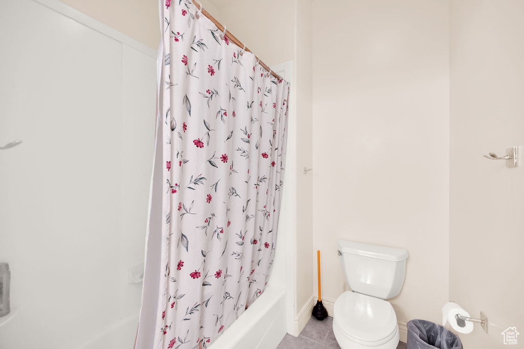 Bathroom with tile flooring, shower / bath combination with curtain, and toilet