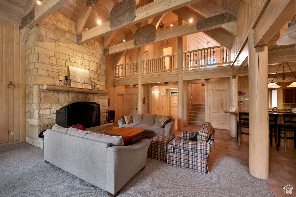 Living room featuring a high ceiling, a stone fireplace, and wood walls