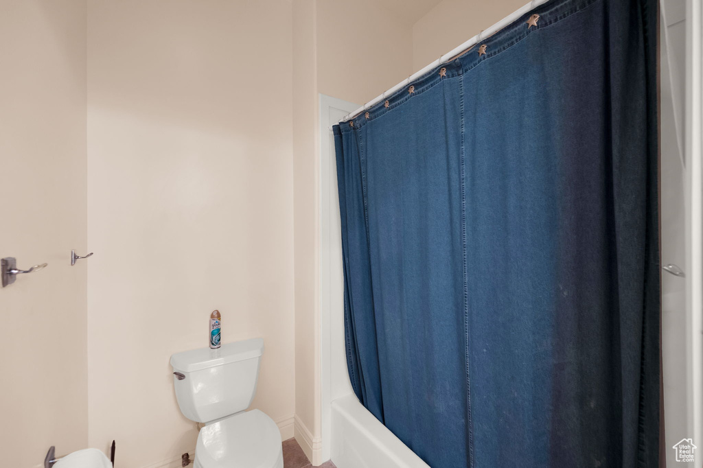 Bathroom with shower / bathtub combination with curtain and toilet