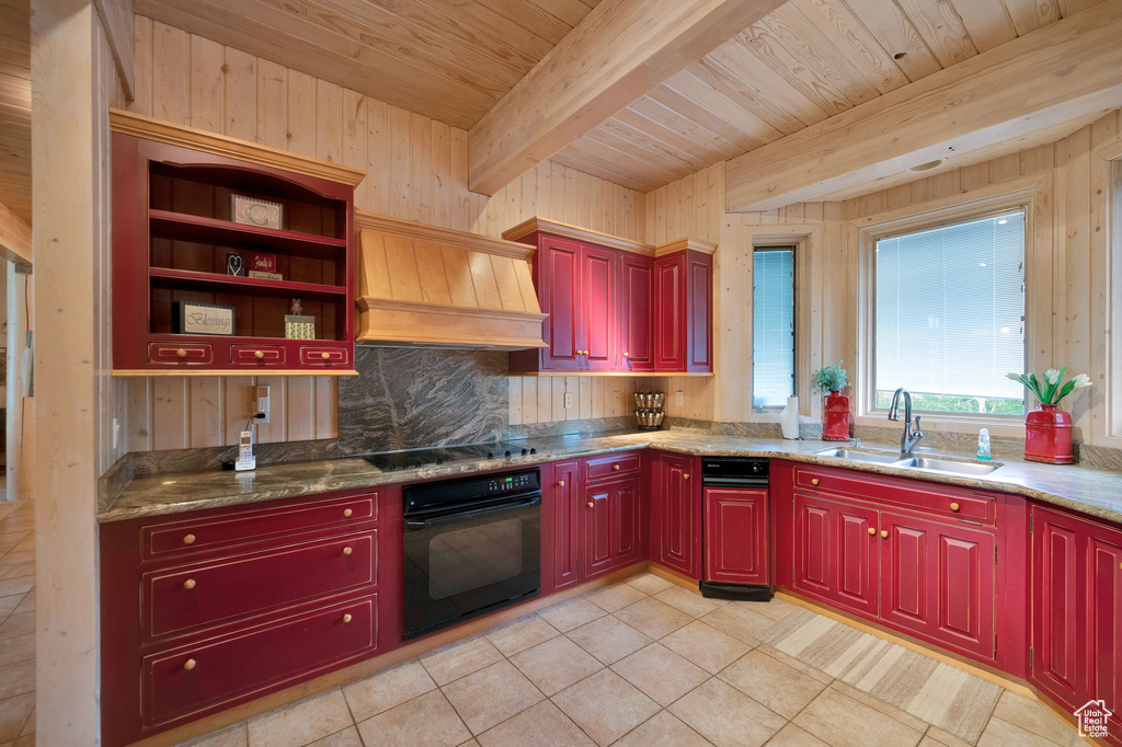 Kitchen with light stone countertops, beam ceiling, custom exhaust hood, and black appliances