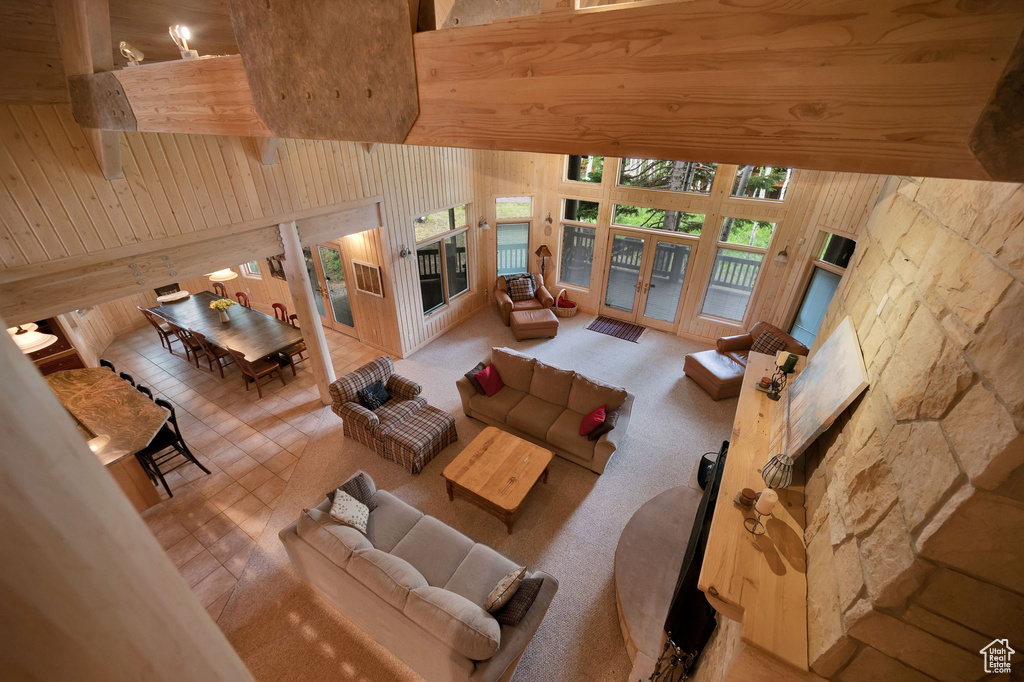 Living room with a high ceiling, wooden walls, and french doors