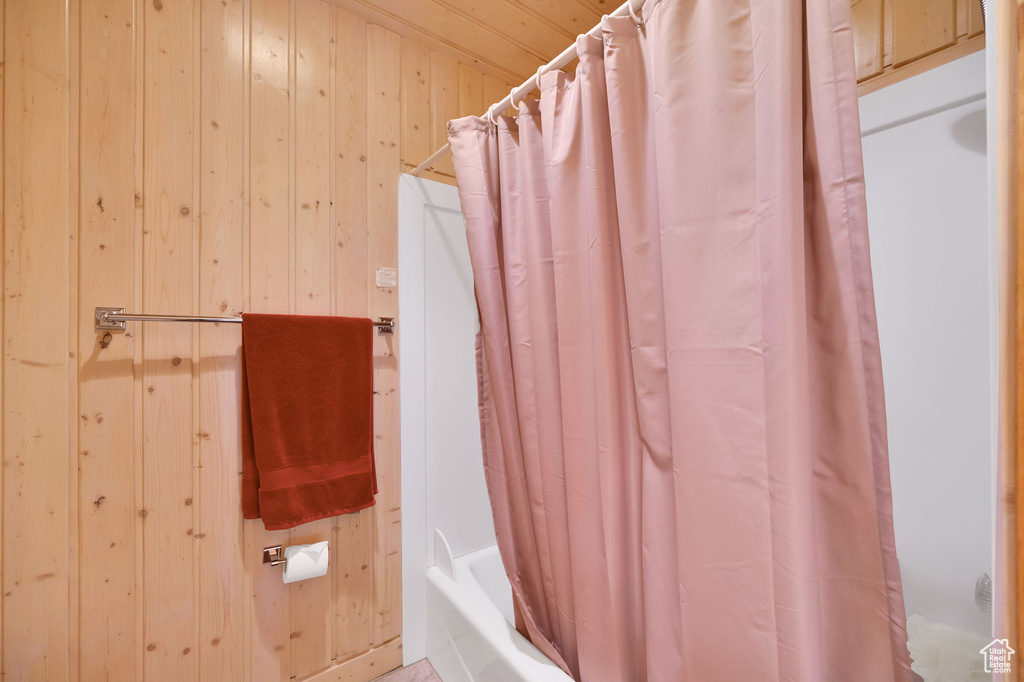 Bathroom with shower / tub combo and wood walls