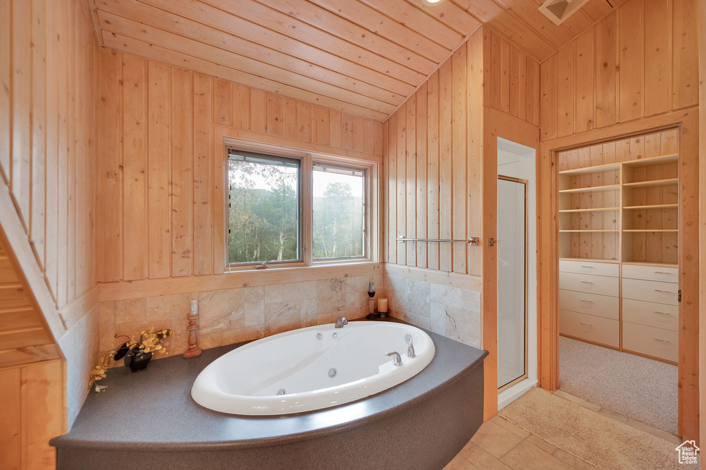 Bathroom featuring vaulted ceiling, wooden walls, wooden ceiling, and plus walk in shower