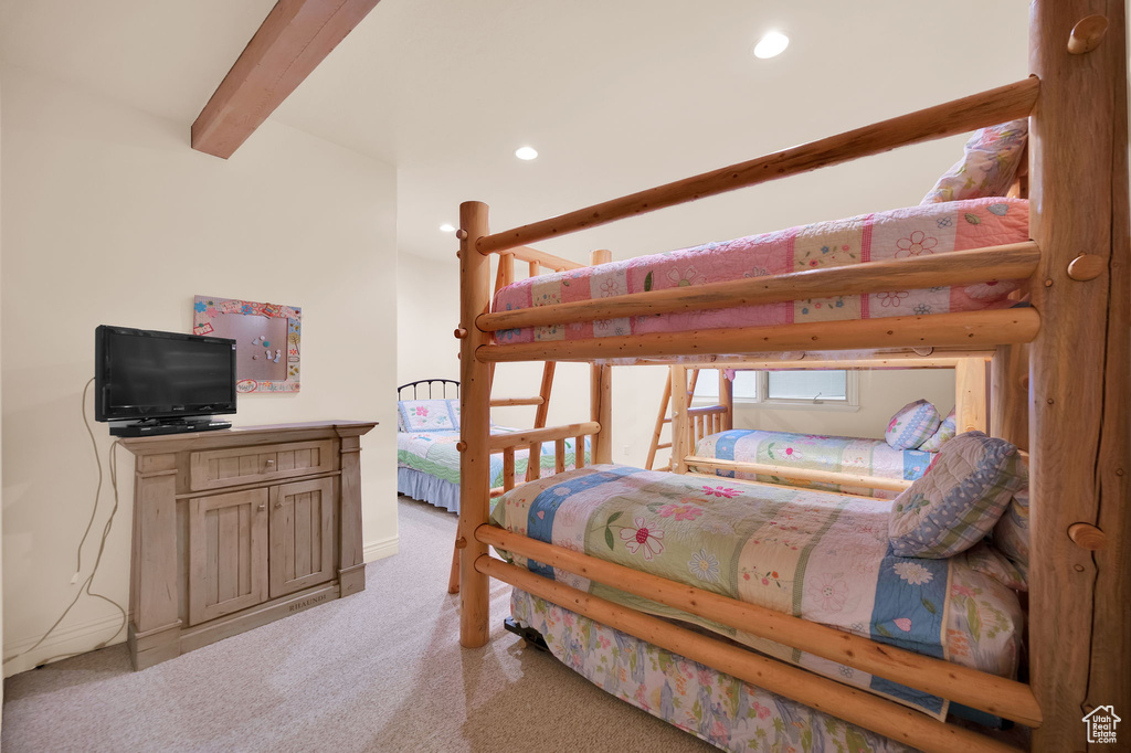 Bedroom featuring light colored carpet and beam ceiling