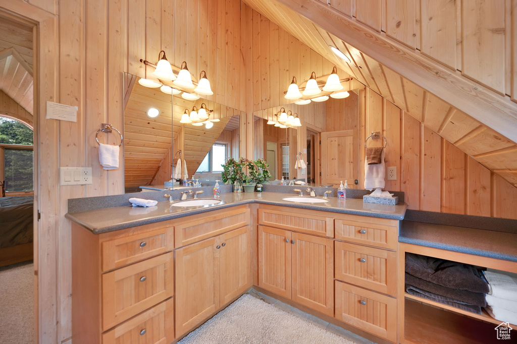 Bathroom featuring lofted ceiling, vanity, and wood walls