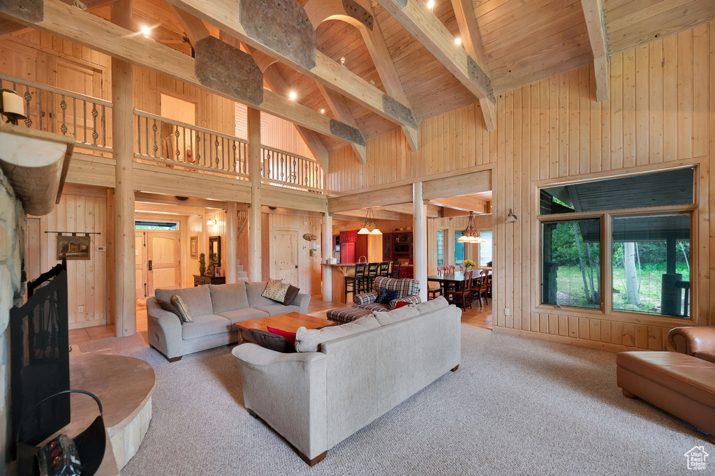 Carpeted living room featuring high vaulted ceiling, wood walls, beamed ceiling, and wood ceiling