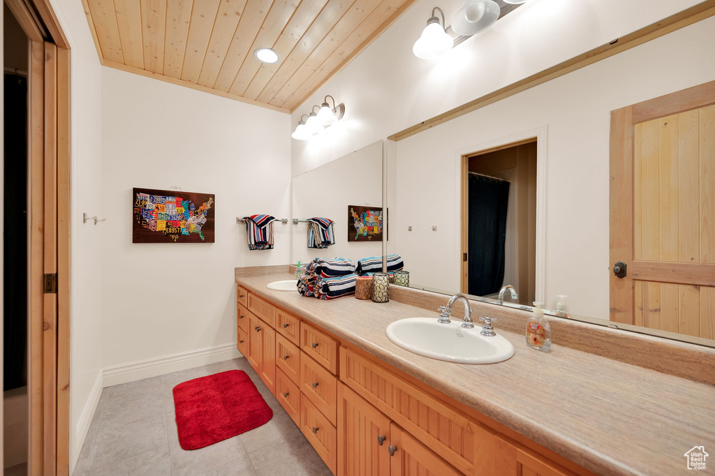 Bathroom with wood ceiling, tile floors, large vanity, and double sink