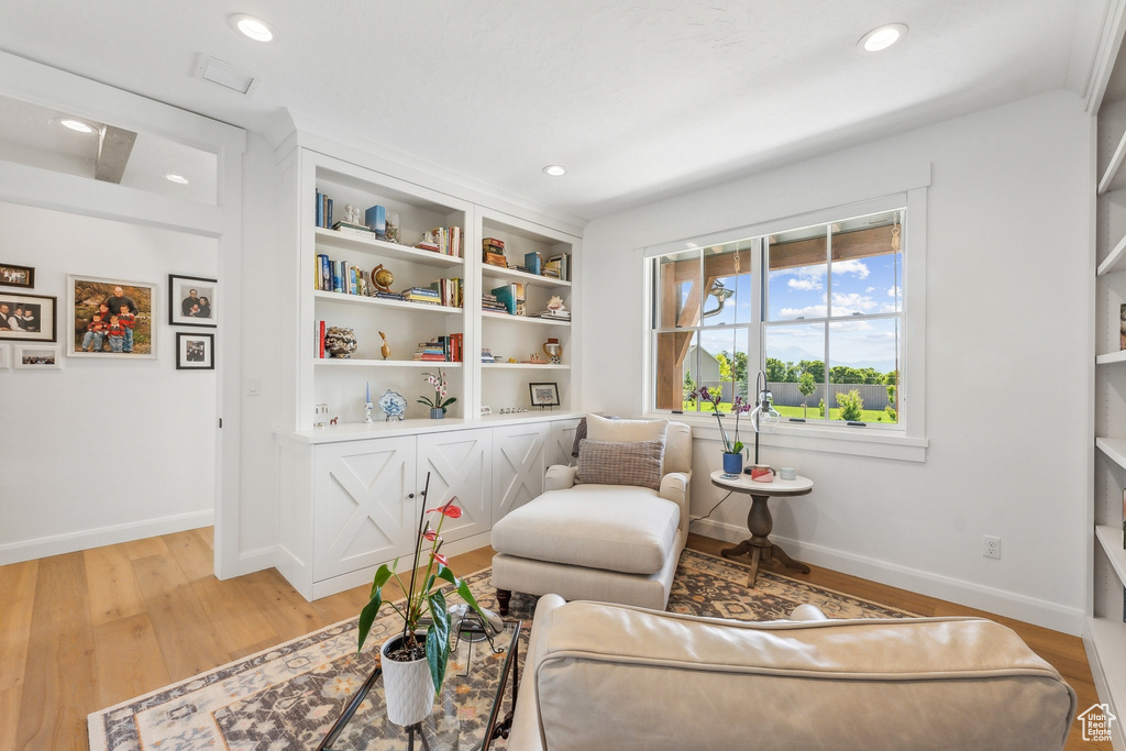 Living room with built in features and wood-type flooring