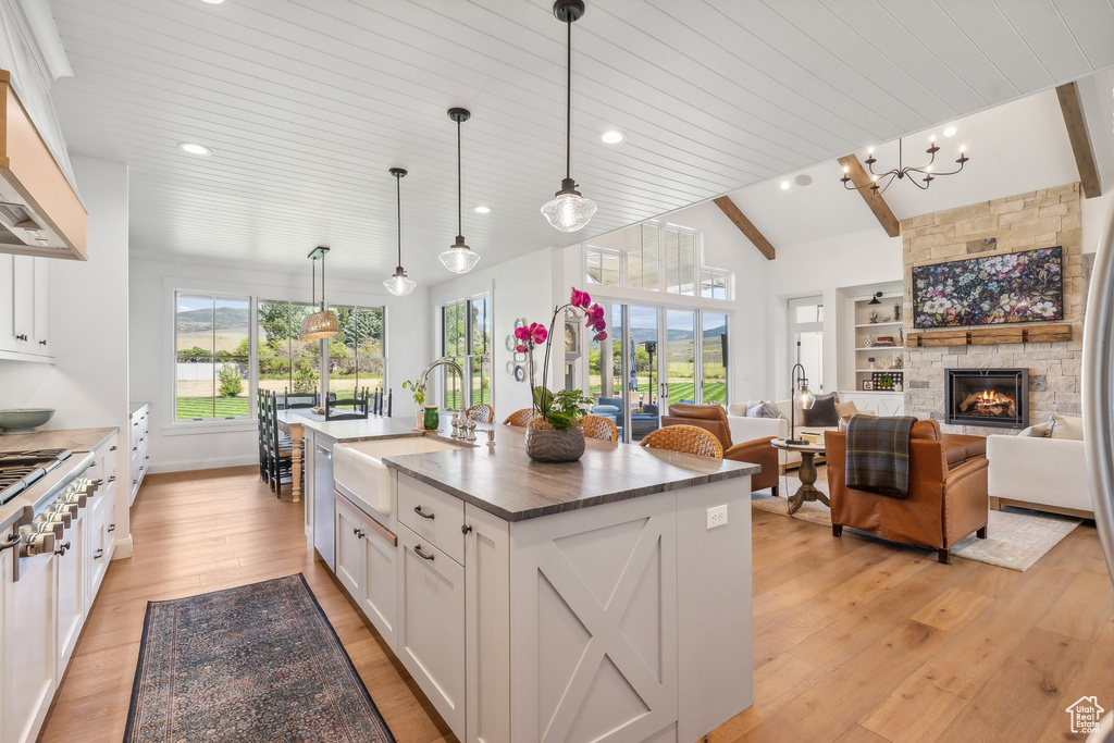 Kitchen featuring an island with sink, plenty of natural light, light hardwood / wood-style floors, and white cabinetry