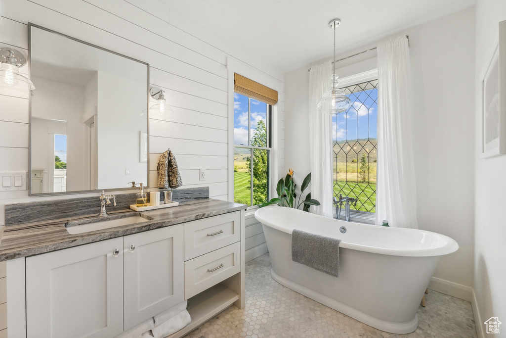 Bathroom with tile floors, vanity, and a tub