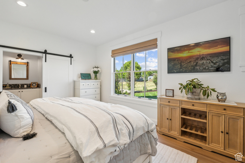 Bedroom with a barn door and light hardwood / wood-style floors