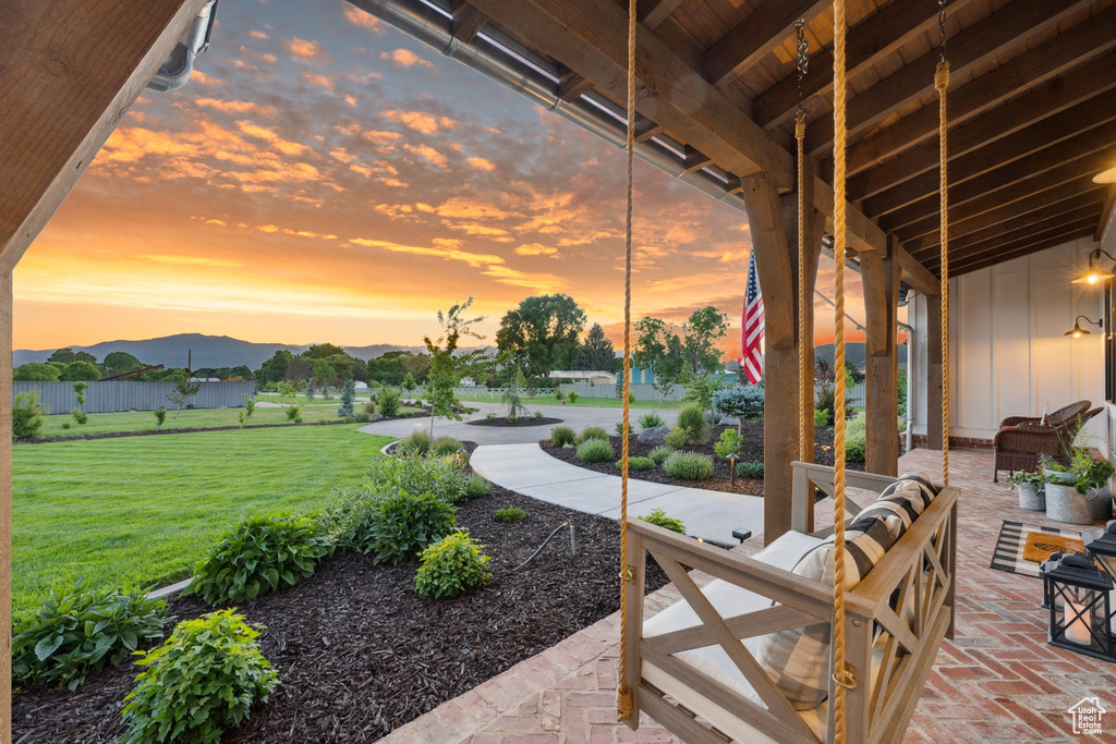 Patio terrace at dusk with a mountain view, a lawn, and an outdoor hangout area