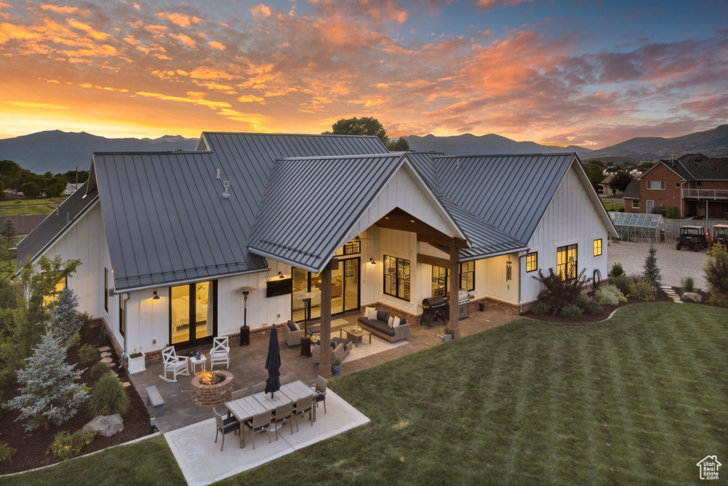 Back house at dusk featuring a patio, a yard, and a mountain view