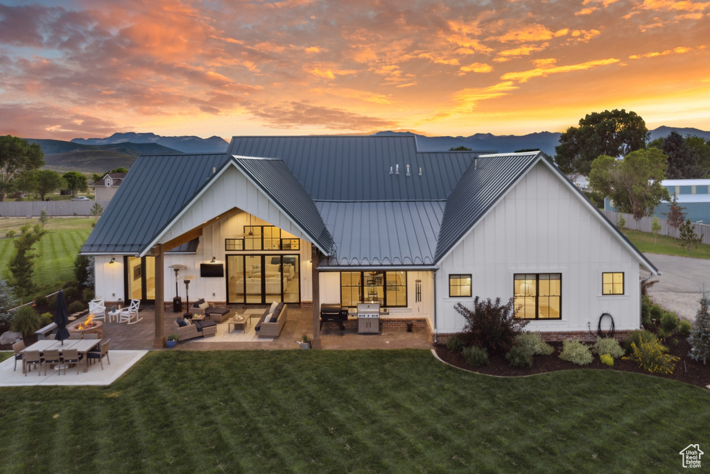 Back house at dusk with a yard, outdoor lounge area, and a patio