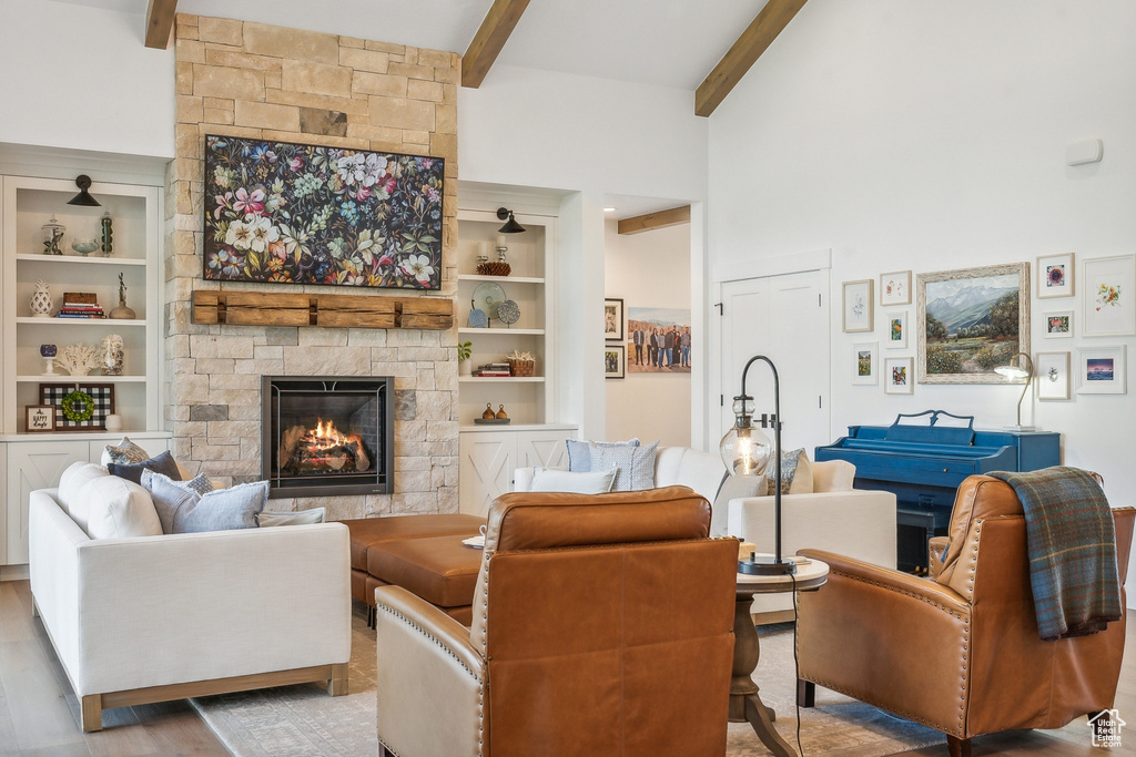 Living room with hardwood / wood-style floors, built in features, beam ceiling, and a fireplace