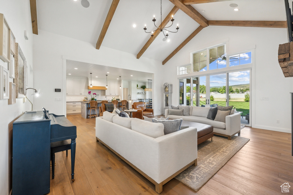 Living room featuring high vaulted ceiling, beamed ceiling, a chandelier, and light wood-type flooring