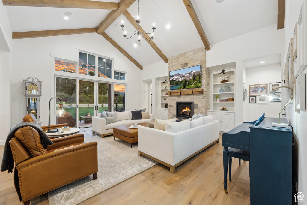 Living room featuring a fireplace, built in features, light wood-type flooring, high vaulted ceiling, and beamed ceiling