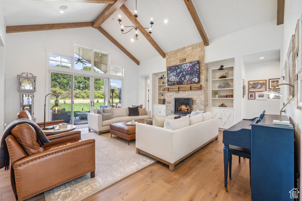 Living room with a fireplace, built in features, hardwood / wood-style floors, beam ceiling, and high vaulted ceiling