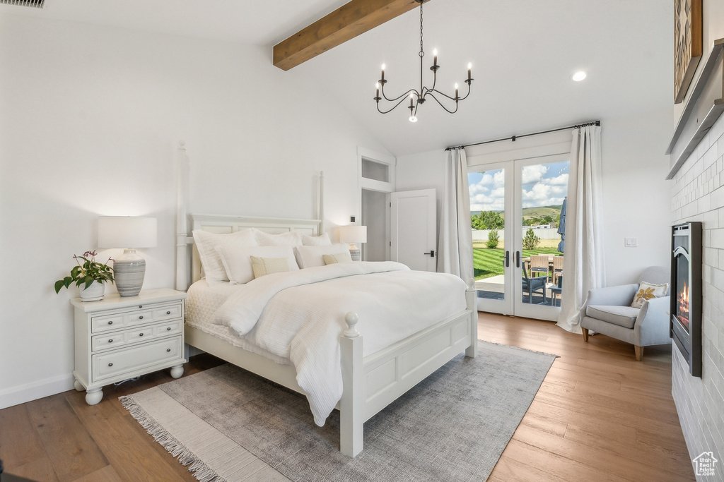 Bedroom with light wood-type flooring, beamed ceiling, access to exterior, a chandelier, and high vaulted ceiling