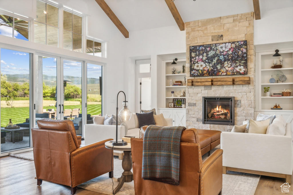 Living room featuring beam ceiling, a fireplace, wood-type flooring, built in features, and high vaulted ceiling