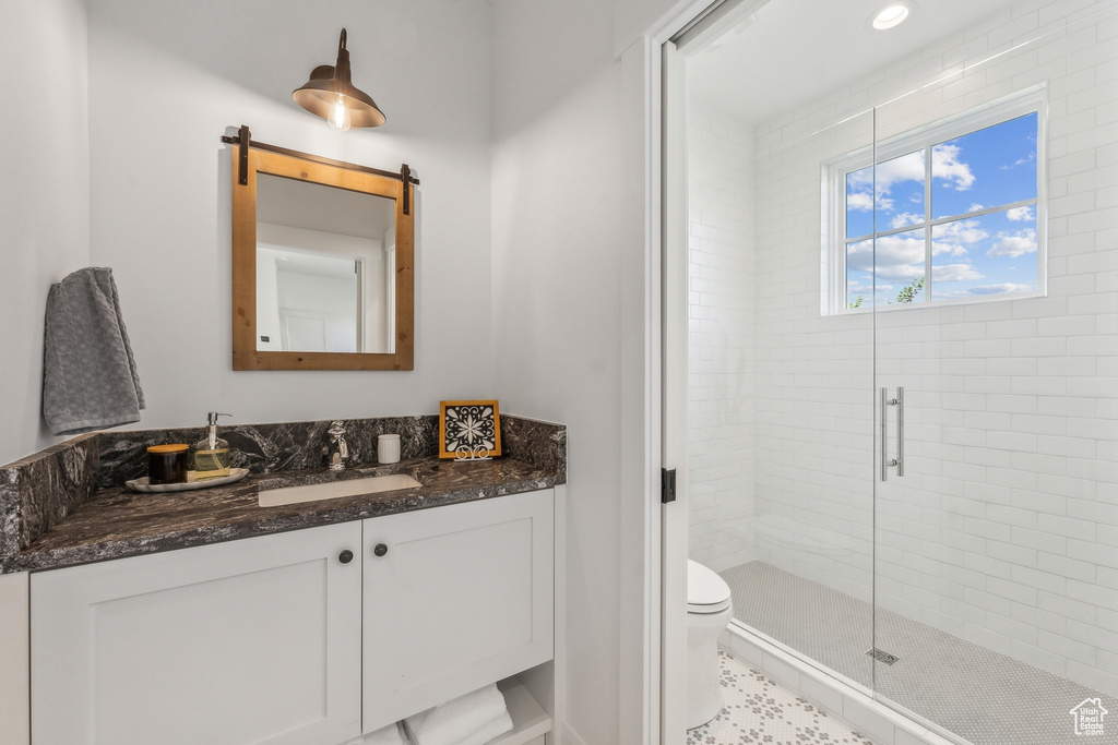 Bathroom with tile floors, a shower with door, vanity, and toilet