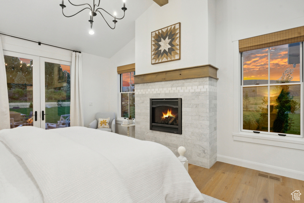 Bedroom featuring light hardwood / wood-style flooring, french doors, a fireplace, access to exterior, and lofted ceiling