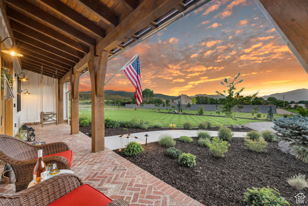 Patio terrace at dusk featuring a lawn