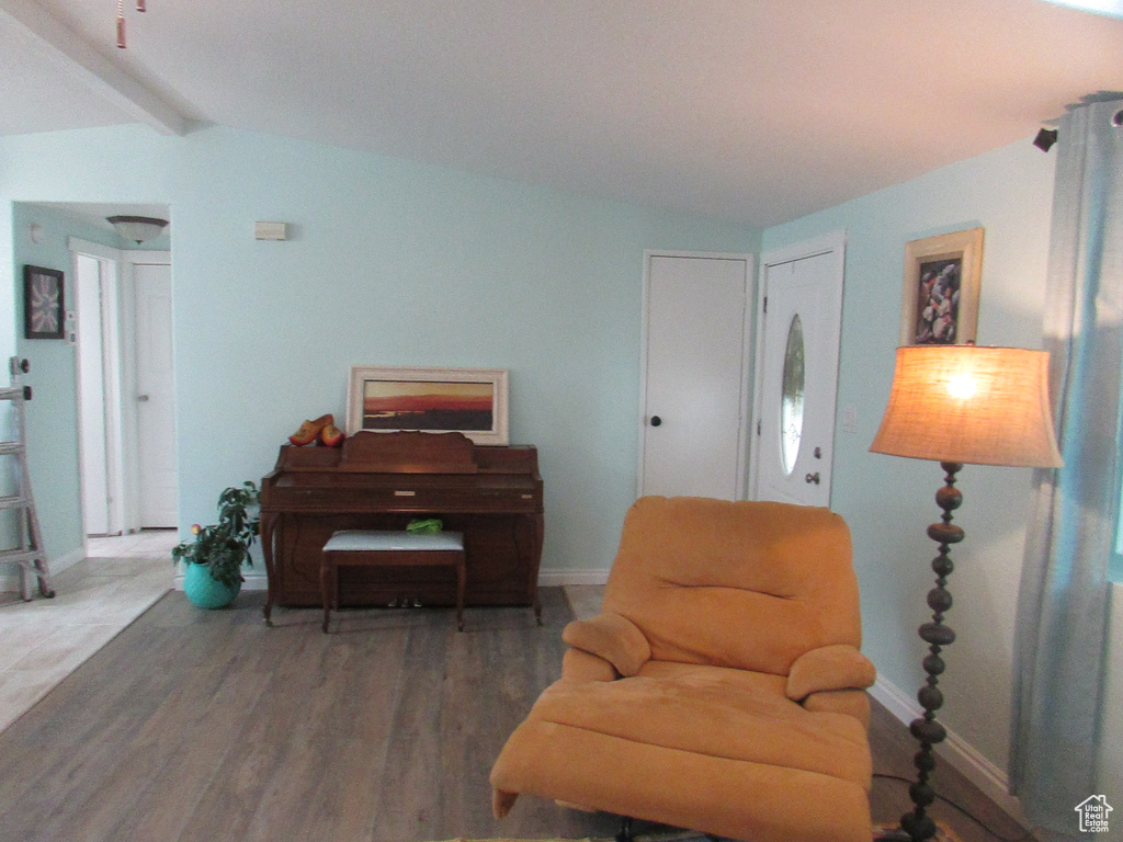 Living area with vaulted ceiling with beams and hardwood / wood-style floors