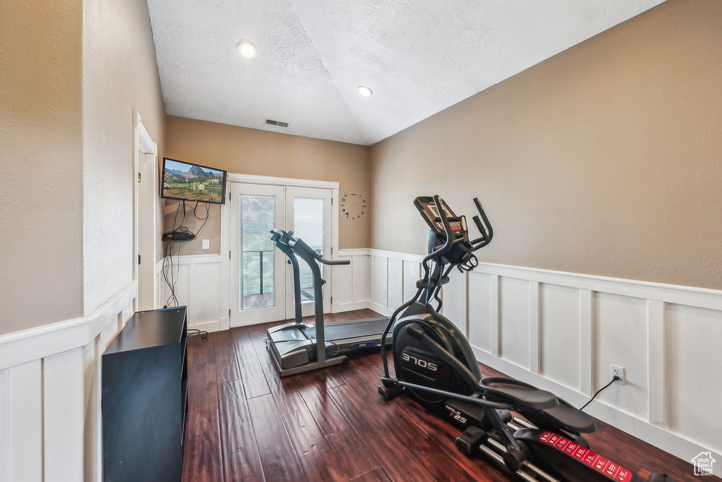 Exercise area with dark hardwood / wood-style floors, french doors, lofted ceiling, and a textured ceiling