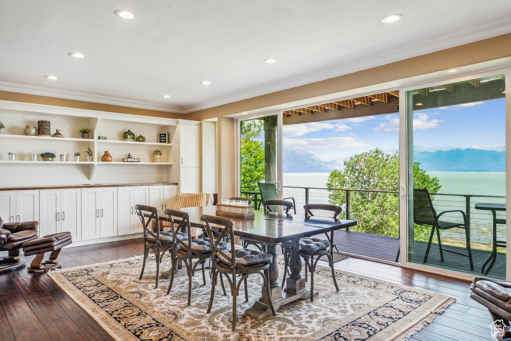 Dining room with built in shelves, crown molding, and dark wood-type flooring