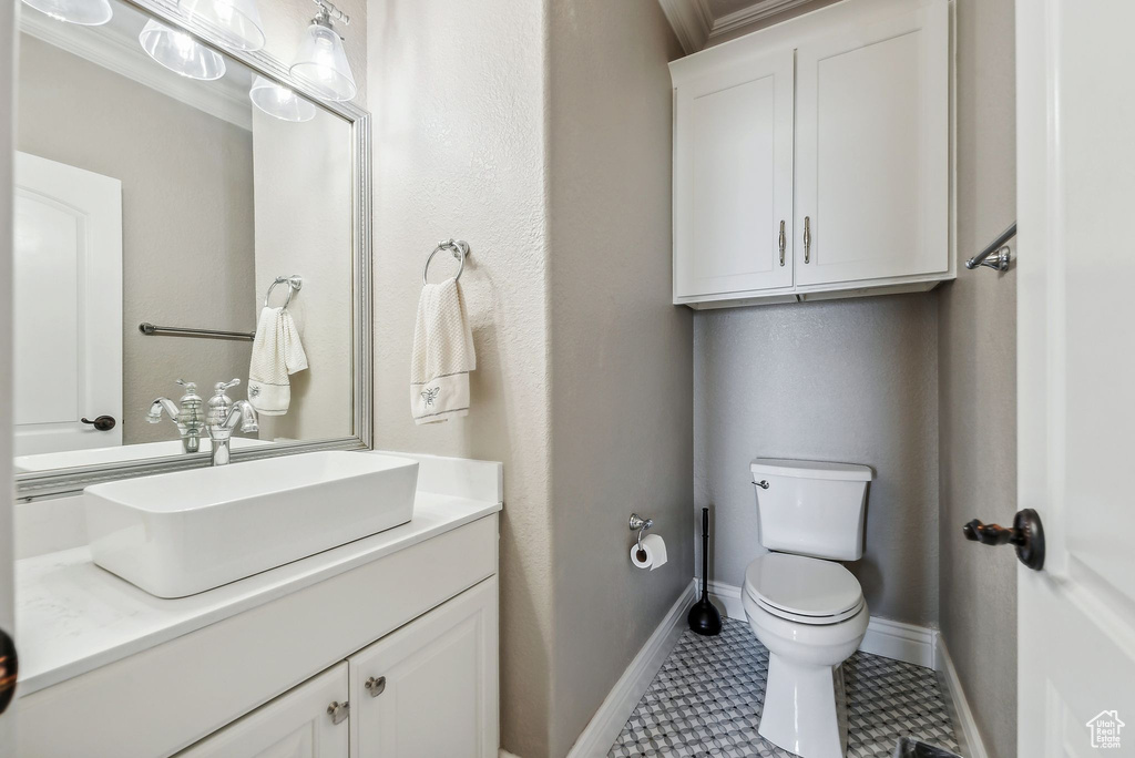 Bathroom with vanity, crown molding, tile patterned flooring, and toilet